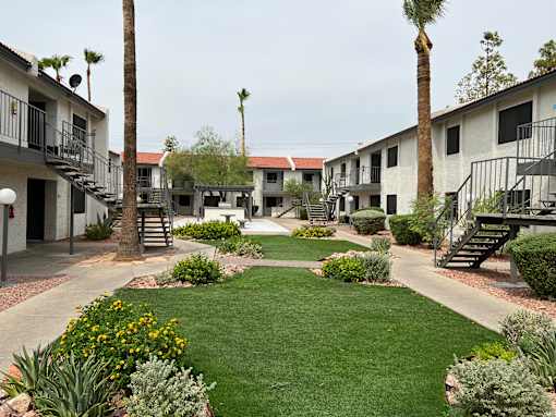 A courtyard with a lawn and a building in the background.