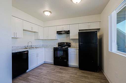 A kitchen with black appliances and white cabinets.
