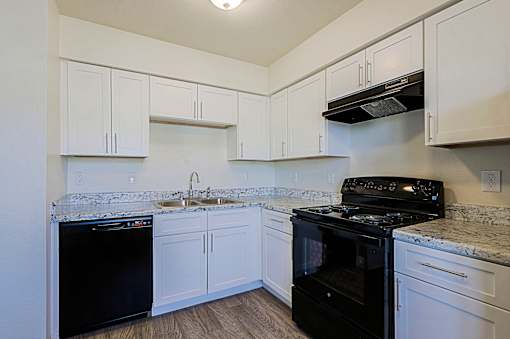 A kitchen with white cabinets and black appliances.