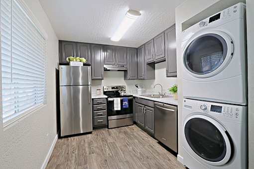A modern kitchen with a refrigerator, oven, and washing machine.