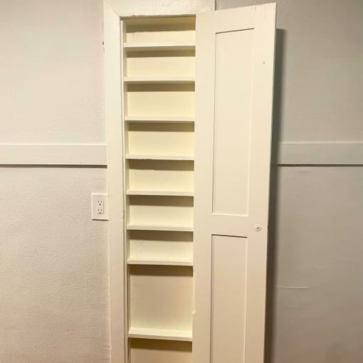 a white bookcase with shelves and a door that is open