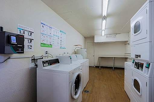 A laundromat with washers and dryers and a wall of posters.