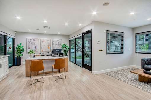 A modern home office with a desk, chairs, and a view of the backyard.