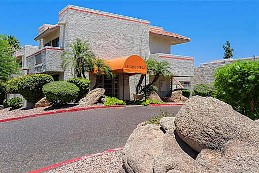 A large rock sits in front of a building with a sign that says "Leasing Office".
