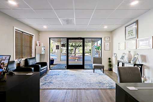 A reception area with a black couch, a desk, and a framed picture on the wall.