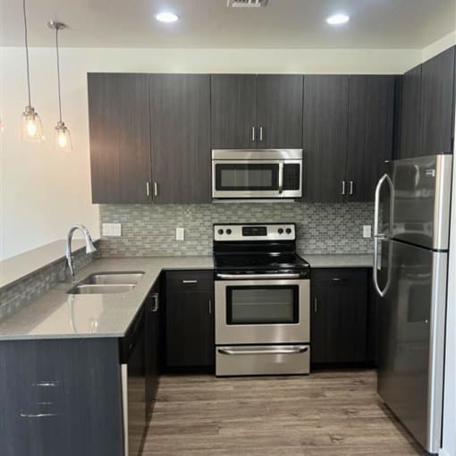 a kitchen with black cabinets and stainless steel appliances