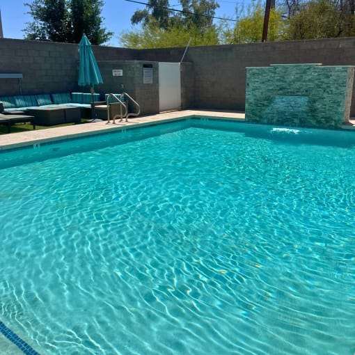 a swimming pool at a hotel with chairs and an umbrella