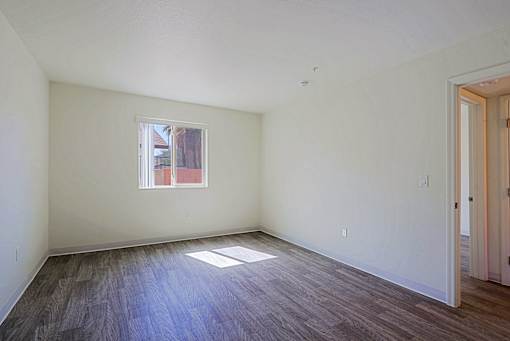 A room with a window and wooden floors.