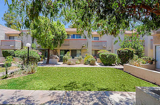 A sunny day at a residential complex with a well-maintained lawn and trees.