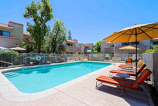 A pool surrounded by chairs and umbrellas.