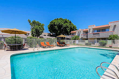 A swimming pool surrounded by a fence and chairs.
