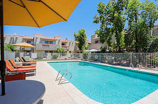 A pool surrounded by chairs and umbrellas.