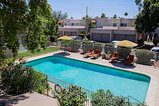 A pool surrounded by chairs and umbrellas.