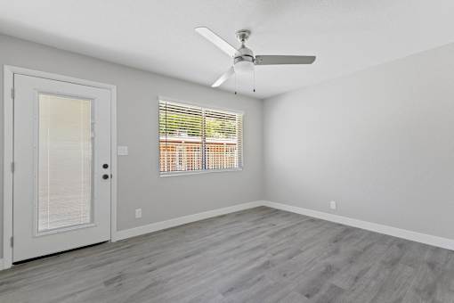 A room with a ceiling fan and a window with blinds.