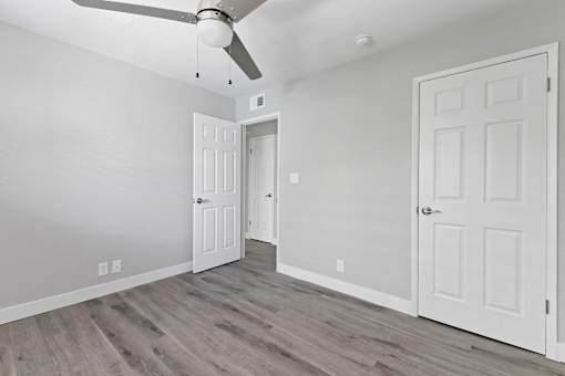 A room with a ceiling fan and two doors.