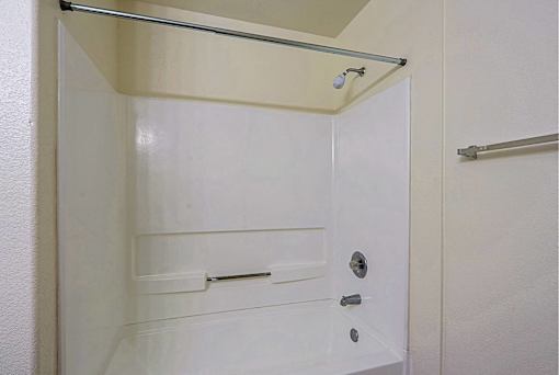 A white bathroom with a shower stall and a towel bar.