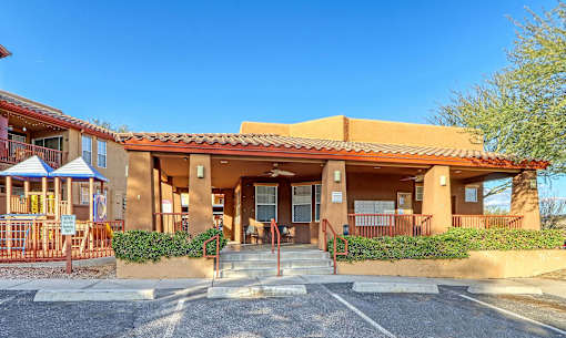 A building with a red roof and a parking lot in front.