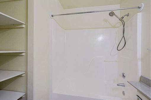A white shower stall with a shower head and hand held shower.