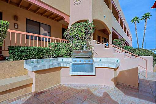 A patio with a grill and a building in the background.