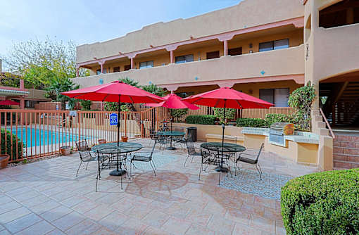 A patio with tables and chairs and umbrellas.