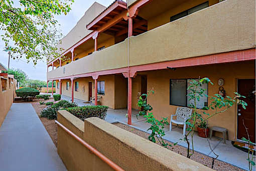 A building with a red roof and a balcony with a chair and table.