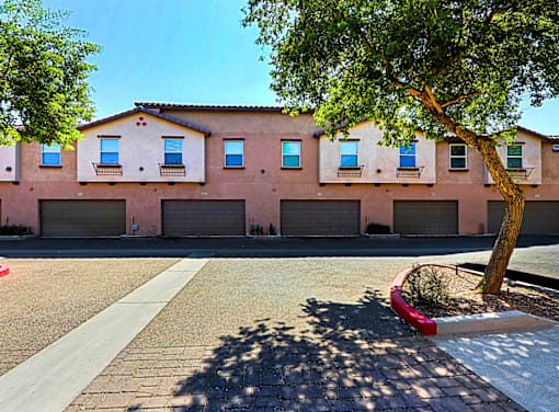 A tree is in front of a building with a red planter.