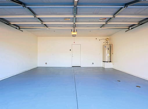 A large empty garage with a door and a wall-mounted heater.