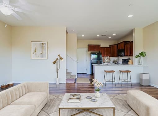 A living room with a white couch, a coffee table, and a kitchen area in the background.