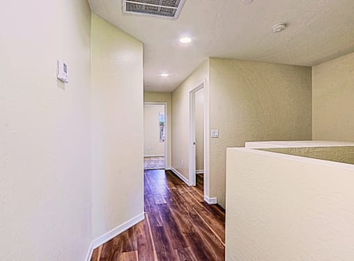 A long hallway with wood floors and white walls.