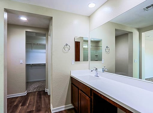 A bathroom with a white counter top and a mirror above it.