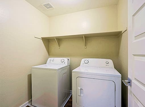 Two white front loading washing machines in a small laundry room.