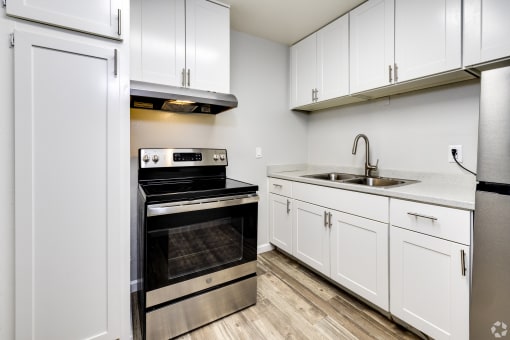 an empty kitchen with white cabinets and stainless steel appliances