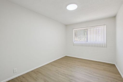 A room with a window and wooden flooring.
