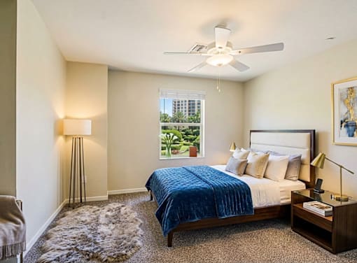 A bedroom with a bed, nightstand, and window.