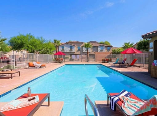A large swimming pool with lounge chairs and umbrellas.