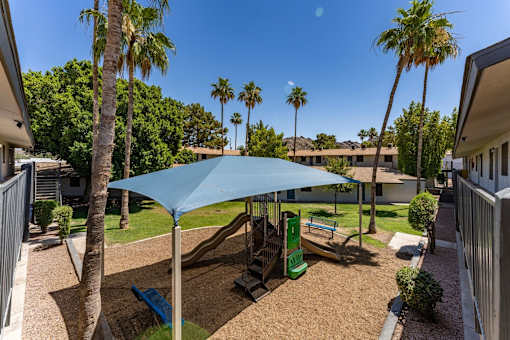 A blue umbrella shades a playground.