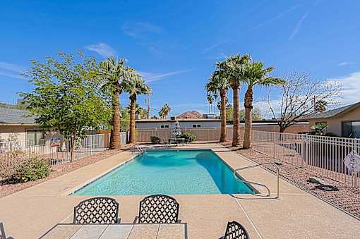 A pool surrounded by palm trees and chairs.