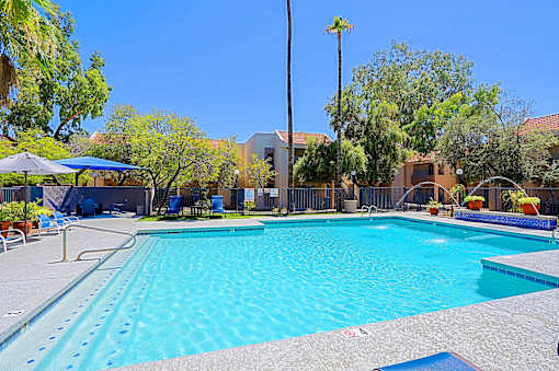 A large swimming pool surrounded by a fence and trees.