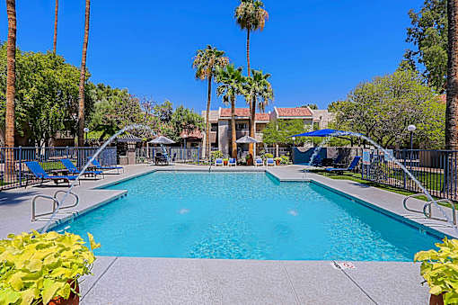 A large swimming pool surrounded by palm trees and lounge chairs.