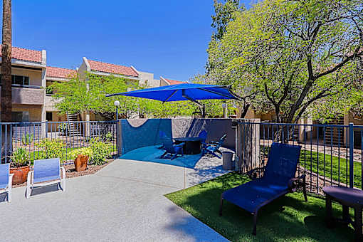 A patio with a blue umbrella and a blue chair.