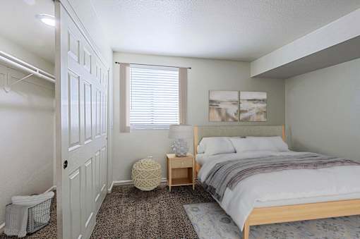 A bedroom with a bed, nightstand, and window.