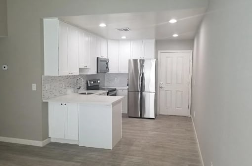 a kitchen with white cabinets and a stainless steel refrigerator