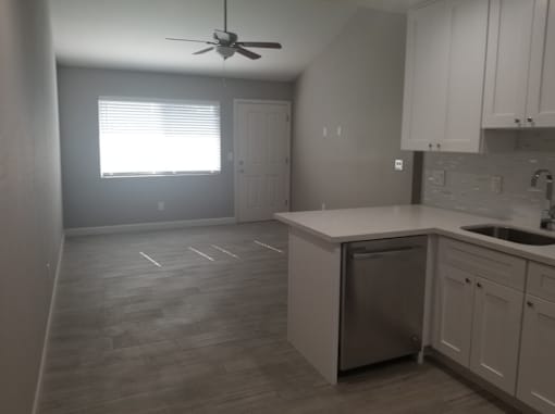 an empty kitchen with a sink and a ceiling fan
