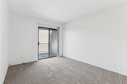 A room with a carpeted floor and a sliding glass door.