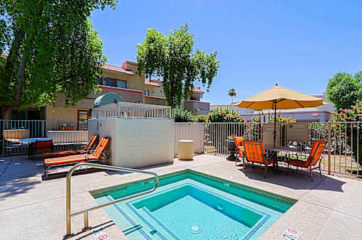 A pool with a slide and chairs around it.