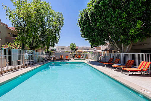 A swimming pool surrounded by trees and chairs.