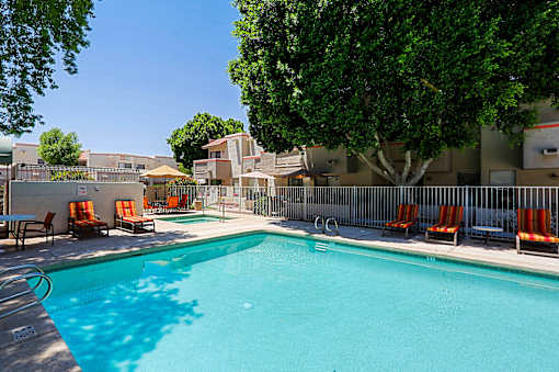 A swimming pool surrounded by trees and chairs.