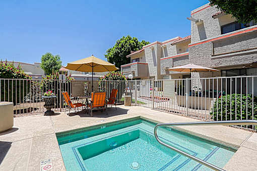 A pool surrounded by a fence and chairs.