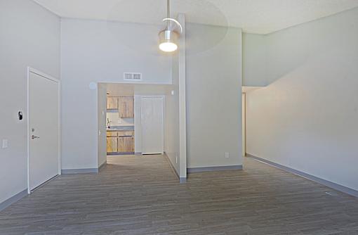 A room with a light hanging from the ceiling and a door on the left at Connect on Northern, Glendale, AZ