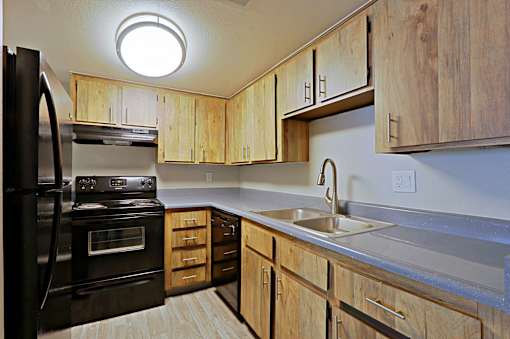 A kitchen with wooden cabinets and a black refrigerator at Connect on Northern, Glendale, AZ